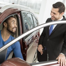 Car shopper sitting in vehicle talking to salesman