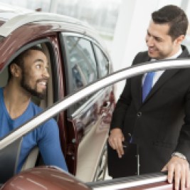 Car shopper sitting in vehicle talking to salesman