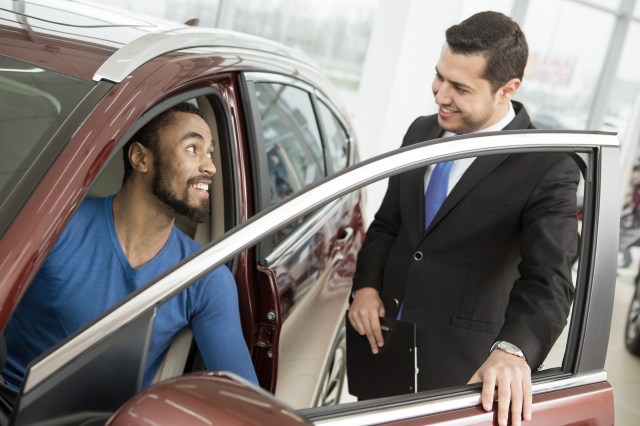 Car shopper sitting in vehicle talking to salesman