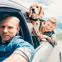 Man and boy traveling with a dog in car