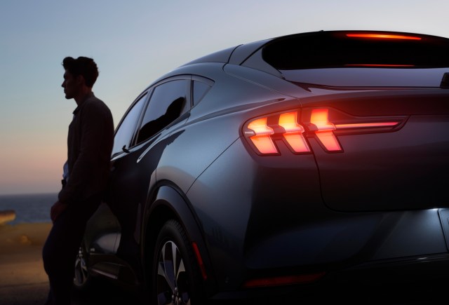Man leaning against car at dusk
