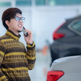 Man car buying on phone in showroom