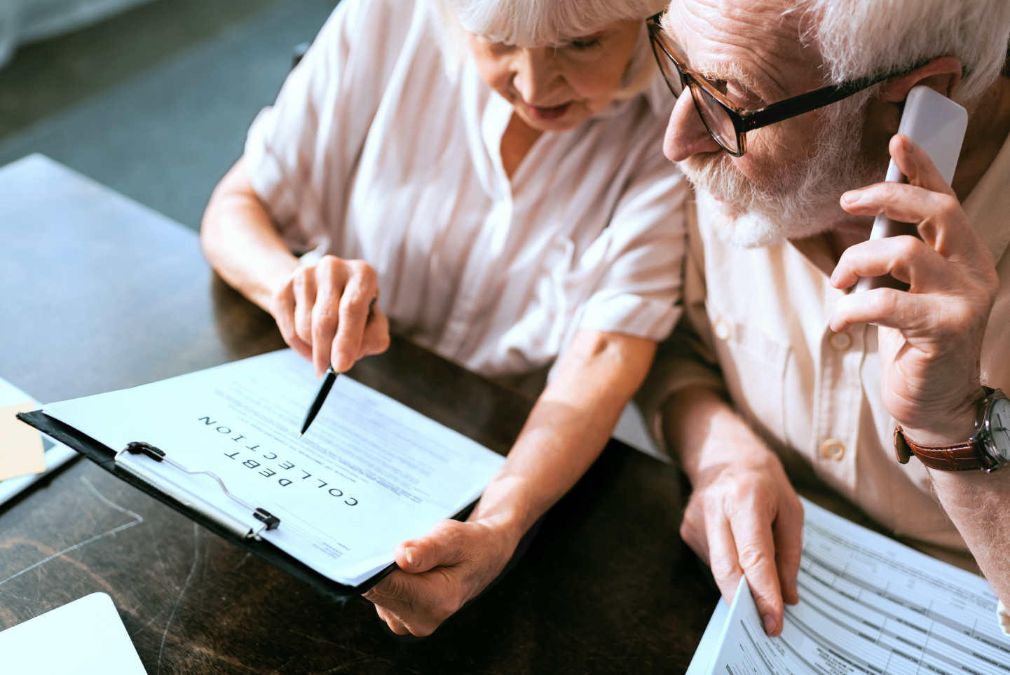 Elderly man on phone, woman holding paperwork