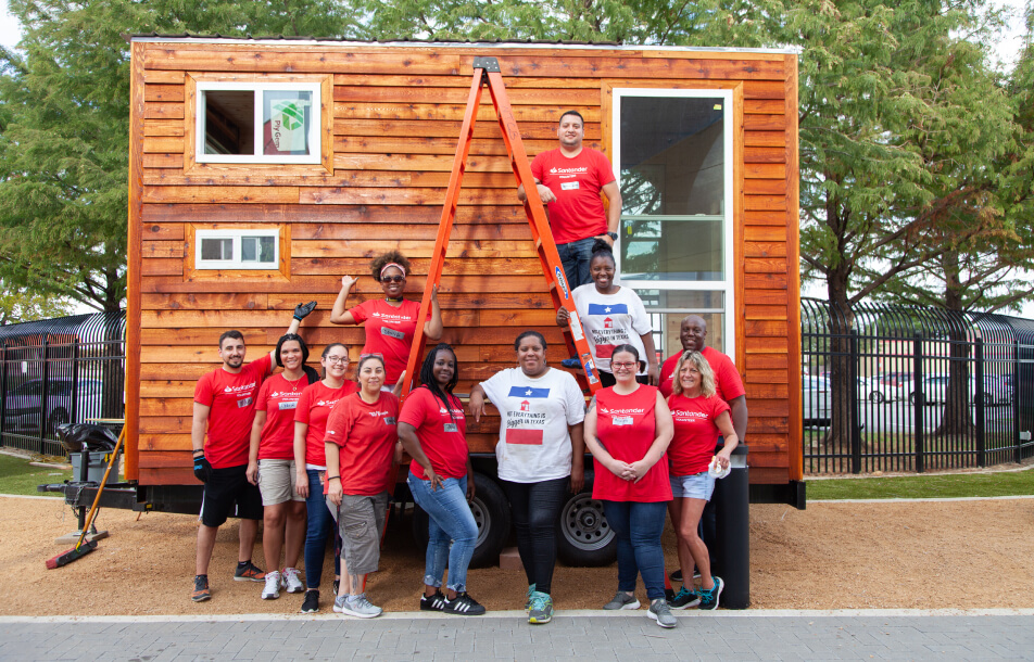 A group of Santander Consumer USA volunteers in front of a tiny house they are building for veterans