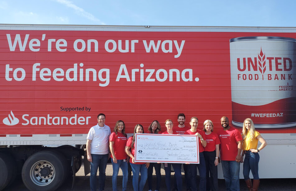 A group of Santander Consumer USA volunteers at a United Food Bank event holding an over-sized donation check.