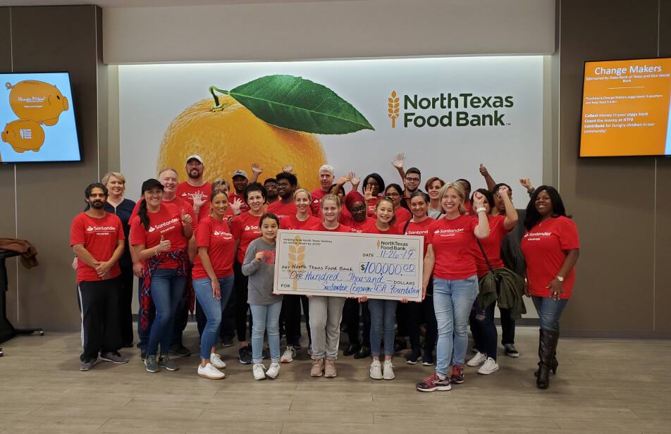 A group of Santander Consumer USA volunteers at a NorthTexas Food Bank event holding an over-sized donation check.