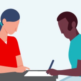 Two people facing each other at a desk with one signing a piece of paper