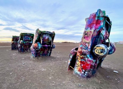 Image of Cadillac cars in a row buried nose first and painted with multi-color spray paint.