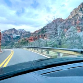 Scene from inside a car looking out along a road and view of mountains