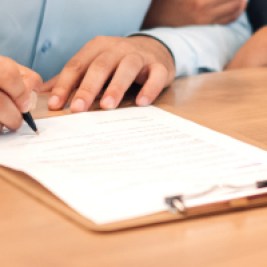 Person signing a contract to buy a car.