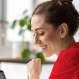 Person smiling and working at a laptop computer.