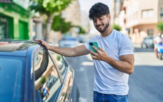 A car buyer stands next to his new vehicle.